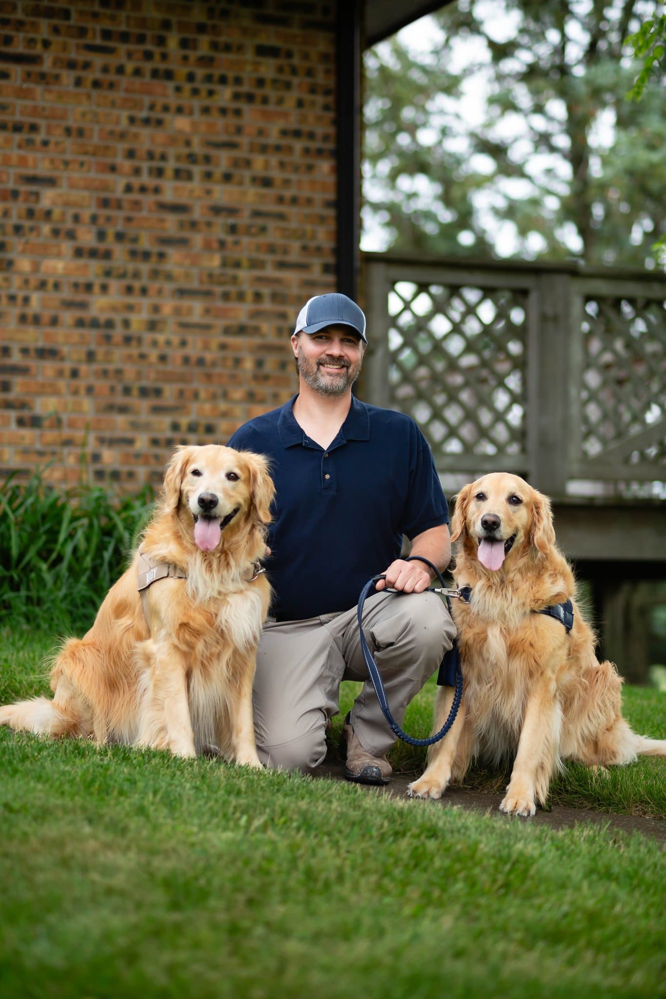 Mike Lacheta kneeling between his two golden retrievers